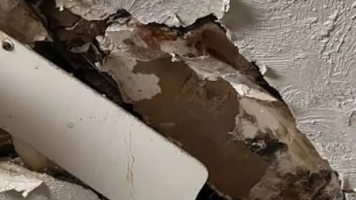 Pipe passing through damaged, peeling plaster